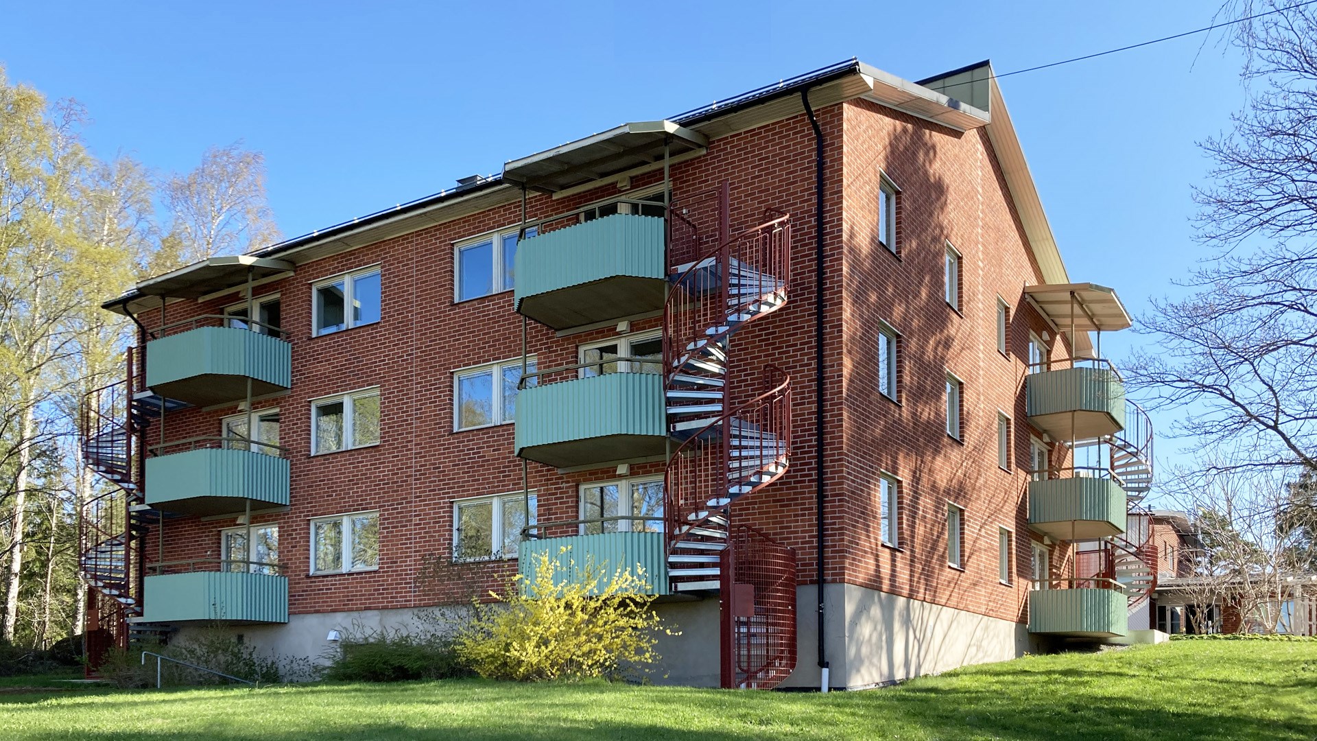 Fasad till trevåningshus med balkonger och spiraltrappor
