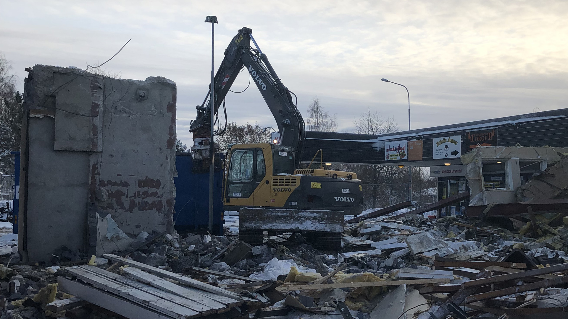 Grävmaskin som river del av en byggnad