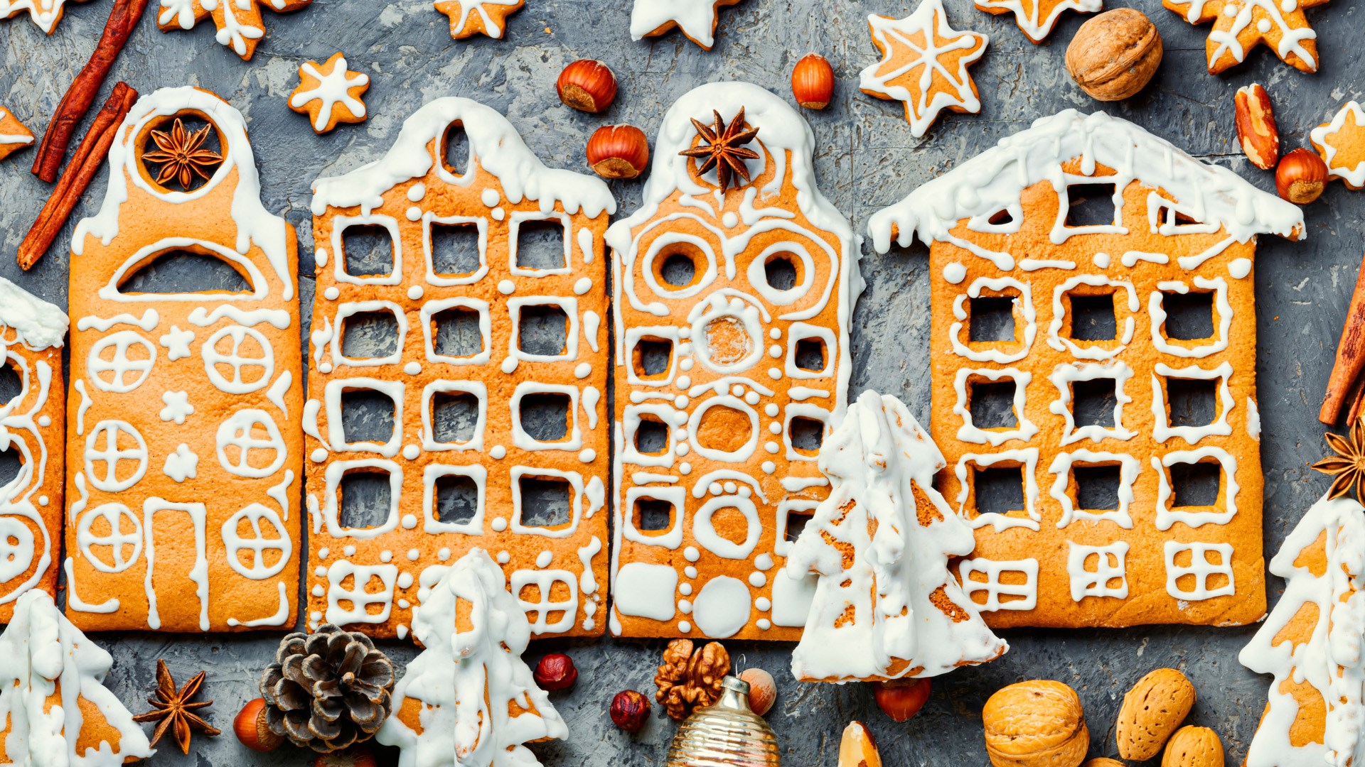 Fasader av flervåningshus i pepparkaka med nötter, kottar och pepparkakor runt om.