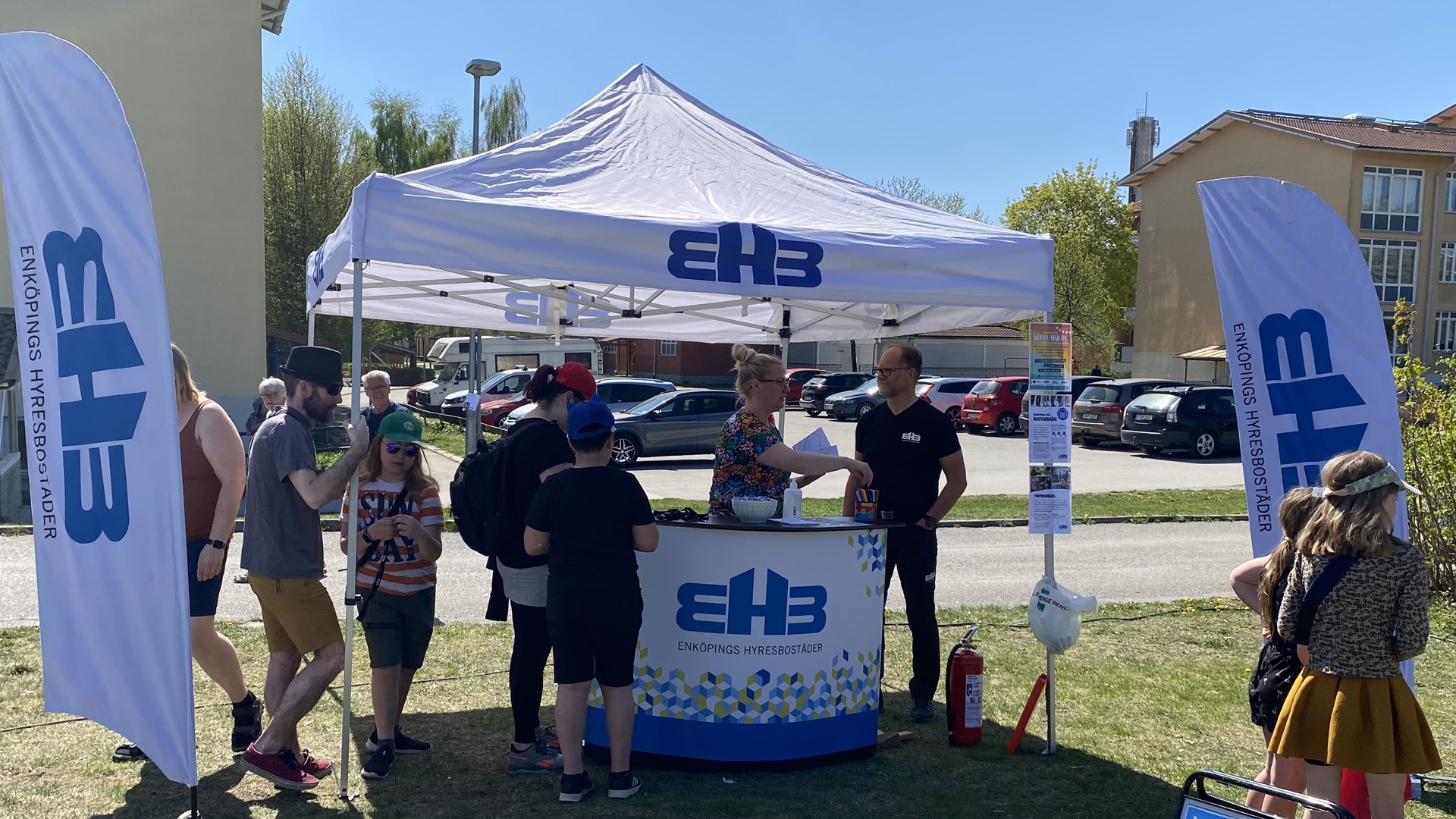 Tält, beachflaggor och disk med EHB:s logo. Besökare pratar med EHB:s medarbetare