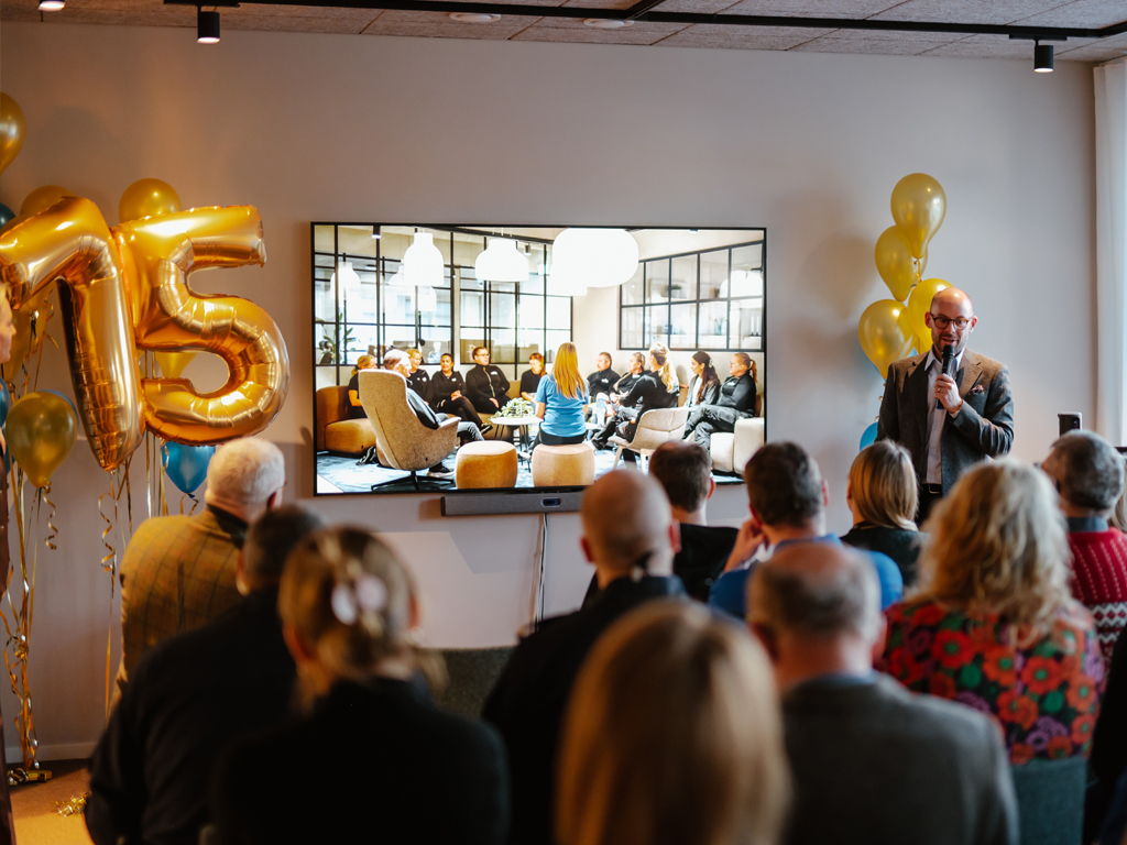 En talare framför en skärm som visar en presentation för åhörarna