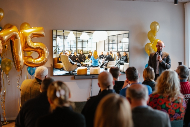 En talare framför en skärm som visar en presentation för åhörarna