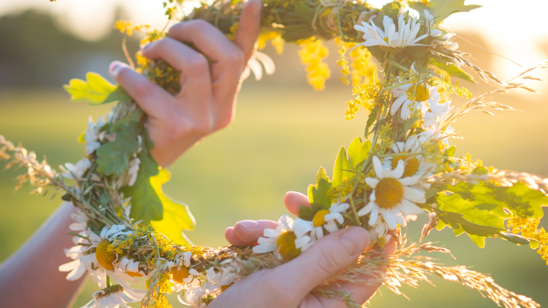 Två händer som håller i en blomsterkrans