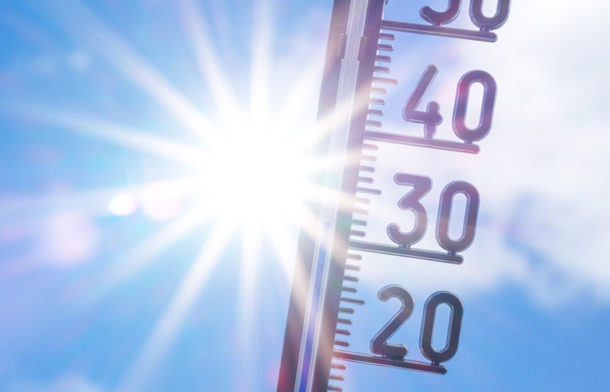 En termometer och visar 31 grader med en strålande sol och blå himmel i bakgrunden