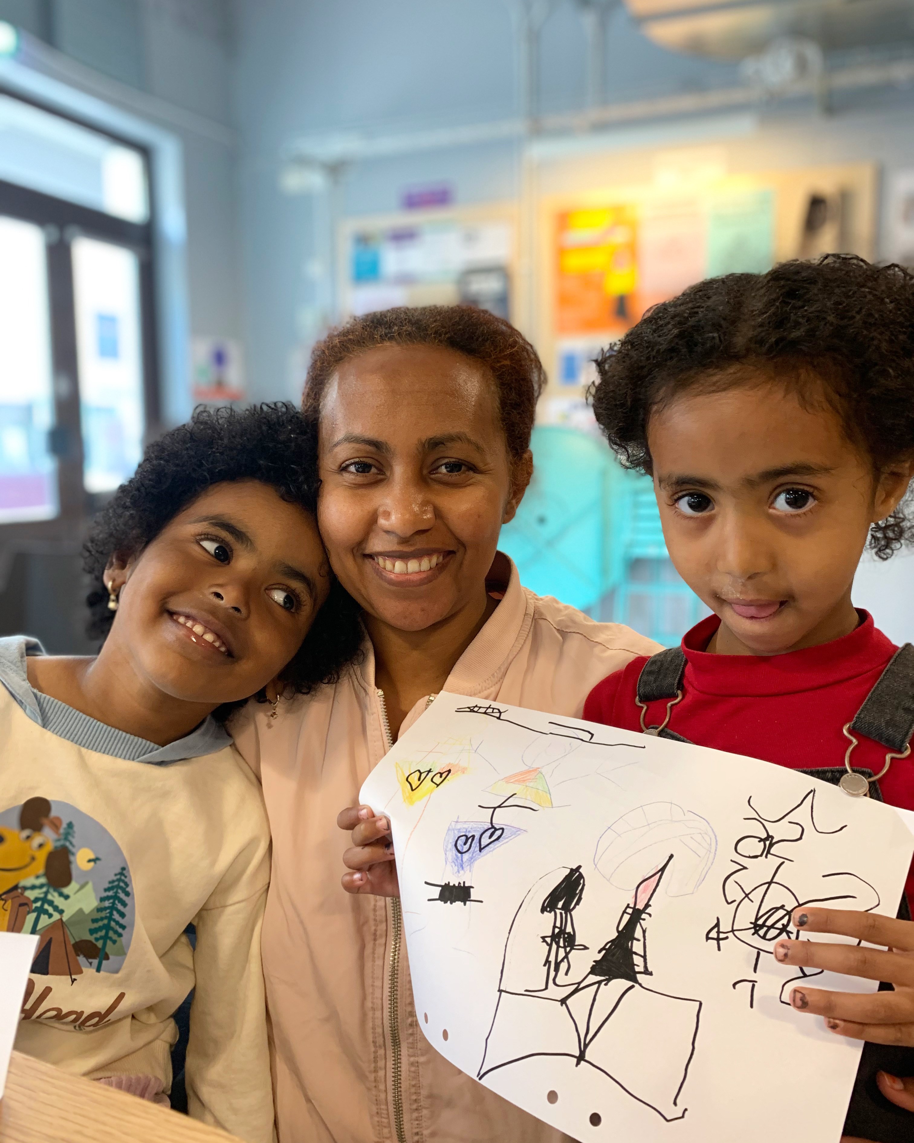 En kvinna med två barn som har ritat på ett papper