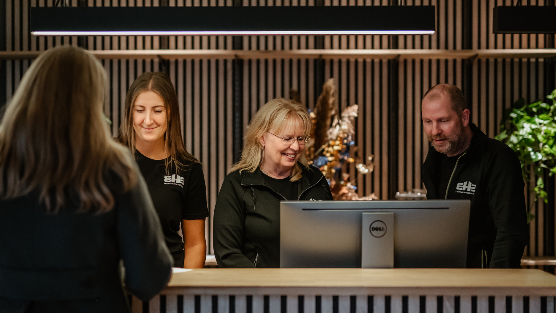 3 personer vid en receptionsdisk som hjälper en besökare